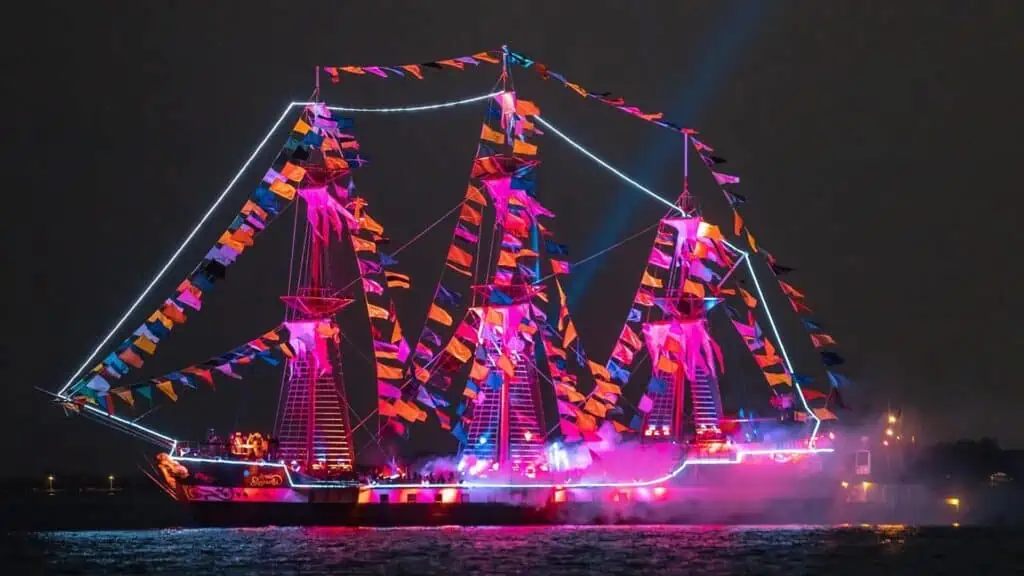 a large pirate shit is bathed in pink lights at night