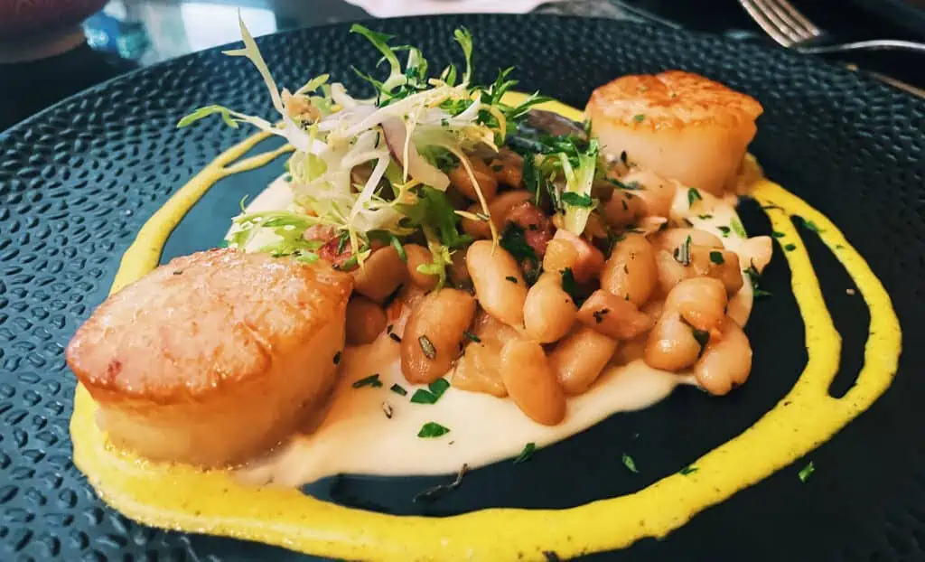 scallops on a black plate with chickpeas