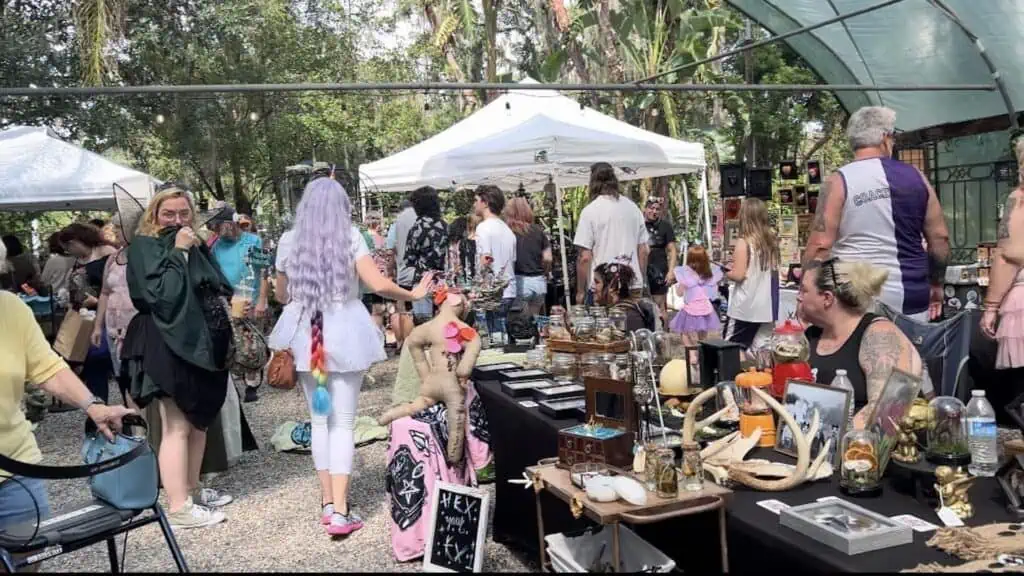 shoppers gather in the woods and browse at multiple booths in a costumed market