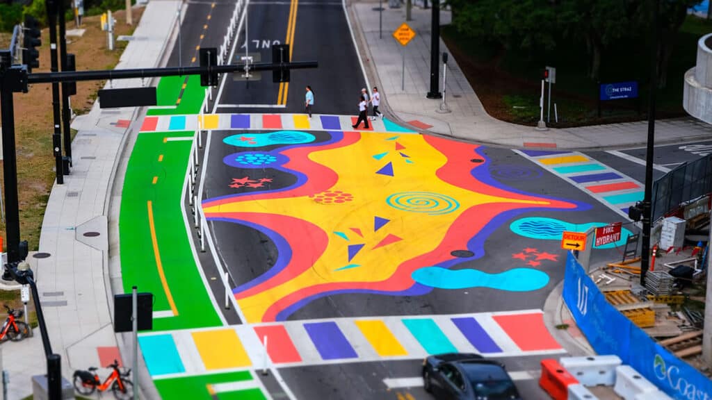 a painted intersection with a green protected bike lane going over a bridge