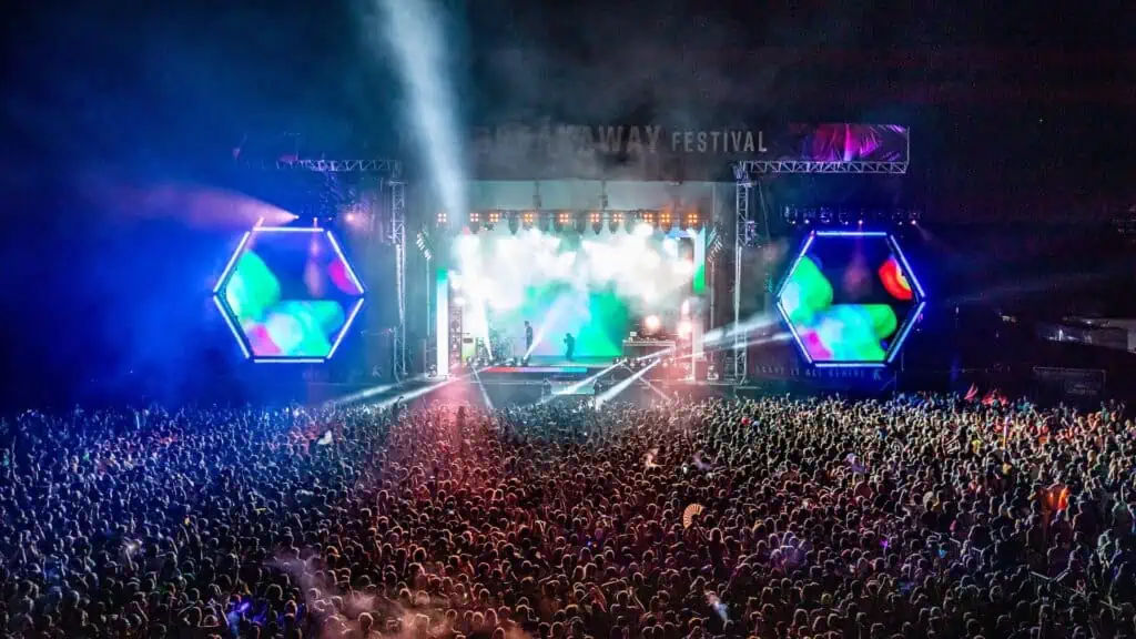 a huge concert stage with thousands of people dancing in the audience