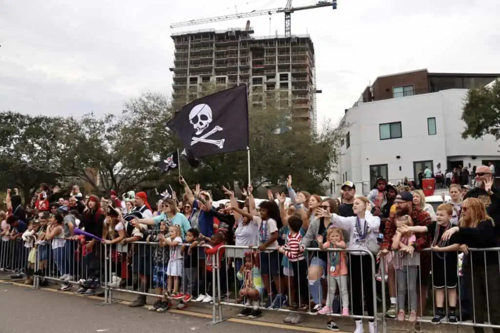 spectators wave a large pirate flag while enjoying a parade