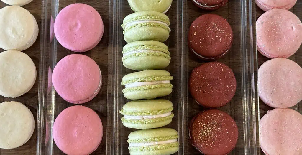 a plate of colorful maacron cookies displayed on a shelf