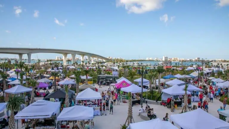 an outdoor market with multiple tents set up along the waterfront