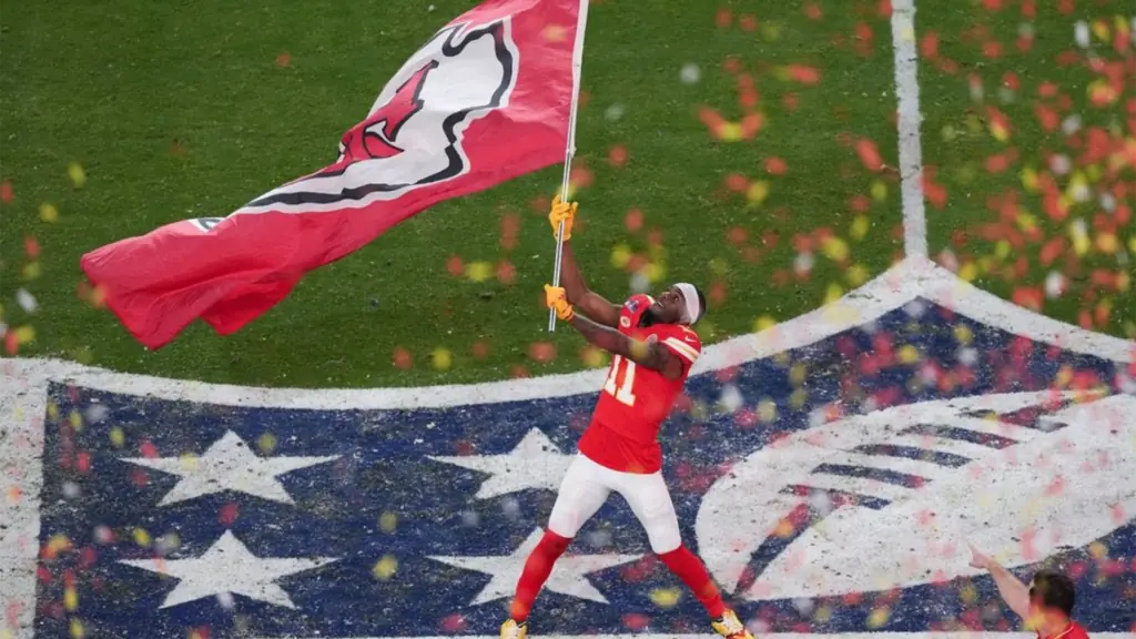 a football player in a red jersey waving a large flag on the field