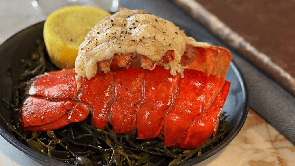 a lobster tail on a plate with a lemon wedge on the side