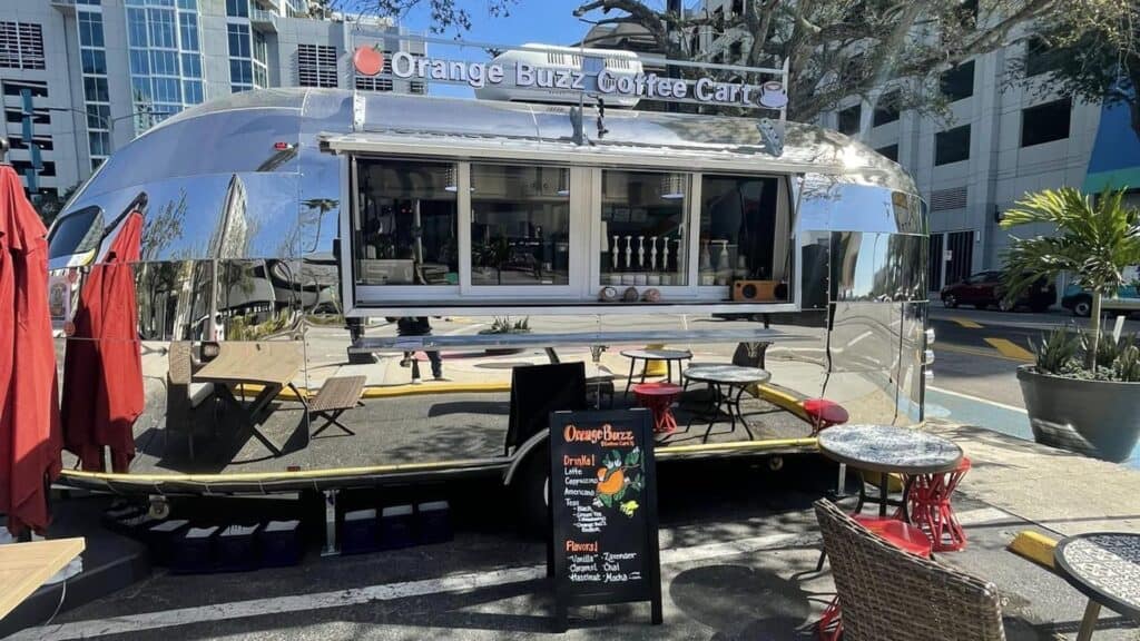 a coffee cart with a big orange sign above the order window.