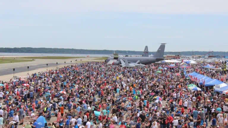 a large airplane at the center of a runway surrounded by spectators
