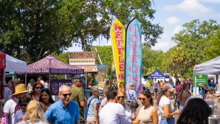 a group of people at an outdoor festival with vendor tents