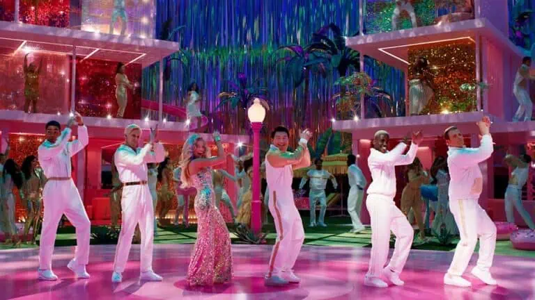 a group of people in sparkling, glittering clothes dances on a pink dance floor