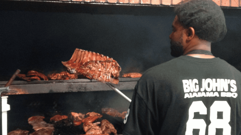 a chef pull a rack of ribs out of a smoker