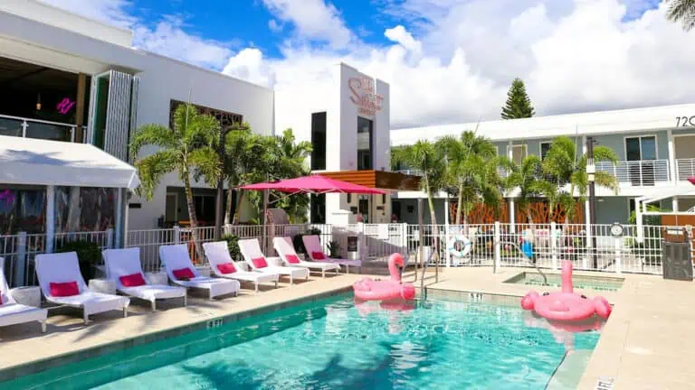 a pool with pink flamingo floats and cabana's