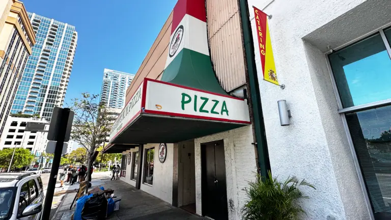 exterior of a pizza restaurant with a large red white and green awning