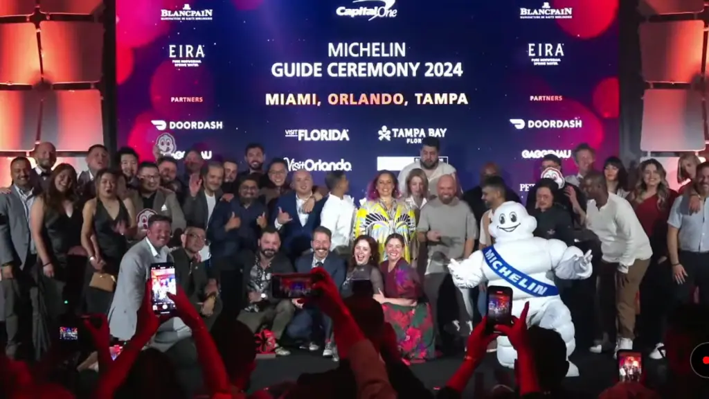 a group of chefs stand on a stage holding awards