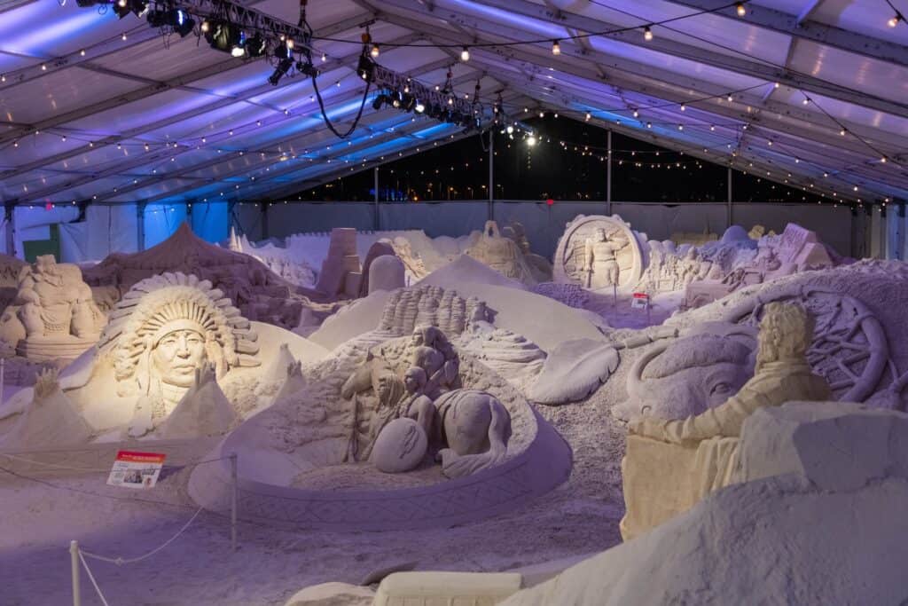 multiple sand sculptures on display under a large open air tent
