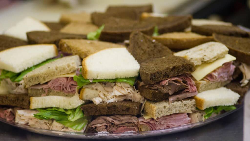 a platter of sandwiches cut into small squares