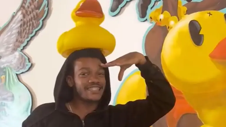 an artist with a rubber duck on their head in a gallery