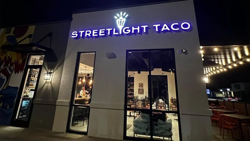 Exterior of a restaurant with a neon sign over the front door.