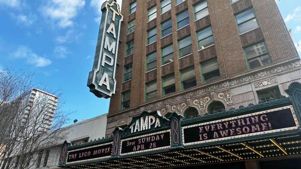 exterior of a movie theatre with a big green sign that reads TAMPA on the outside