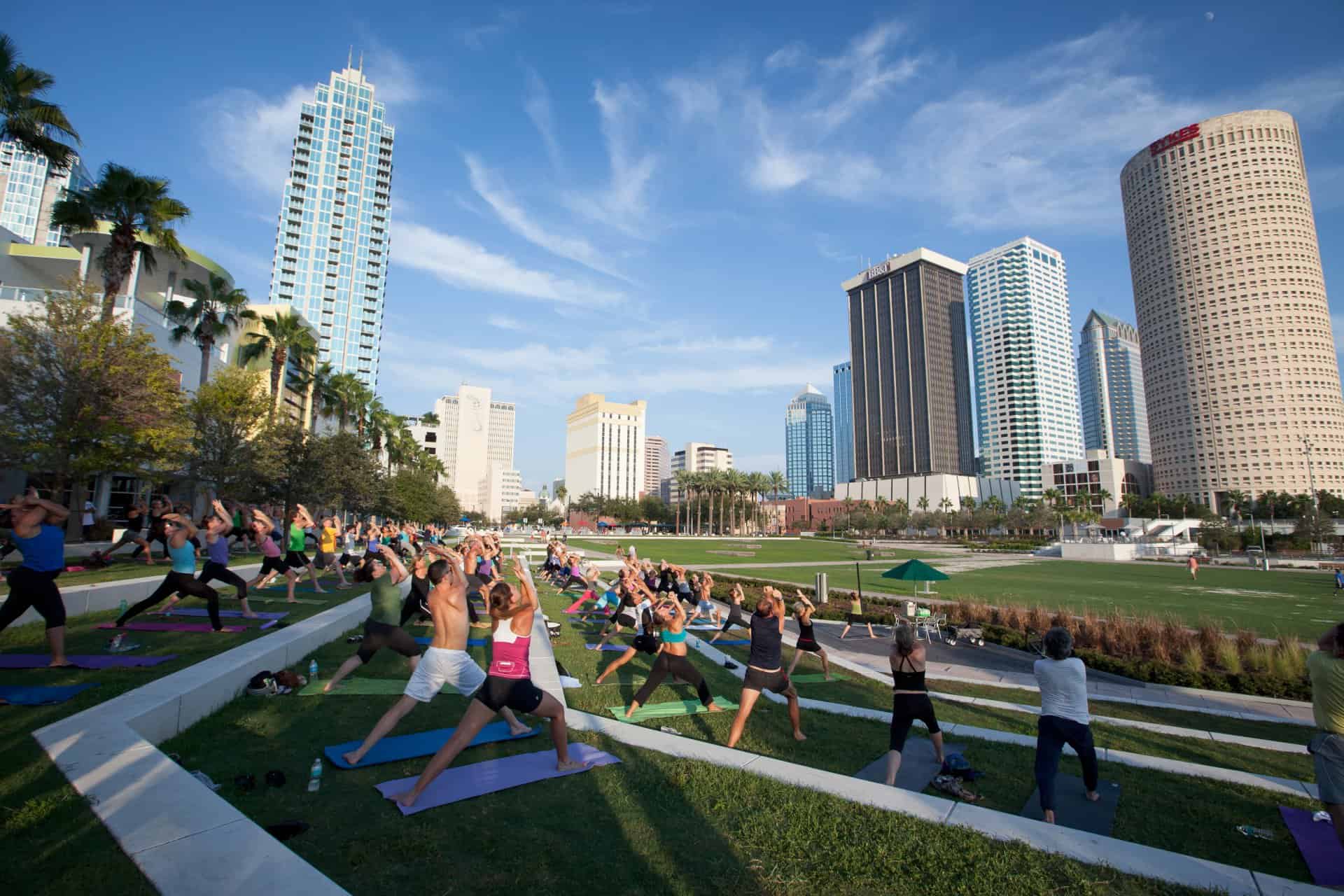 a group of people practice yoga in a large waterfront park
