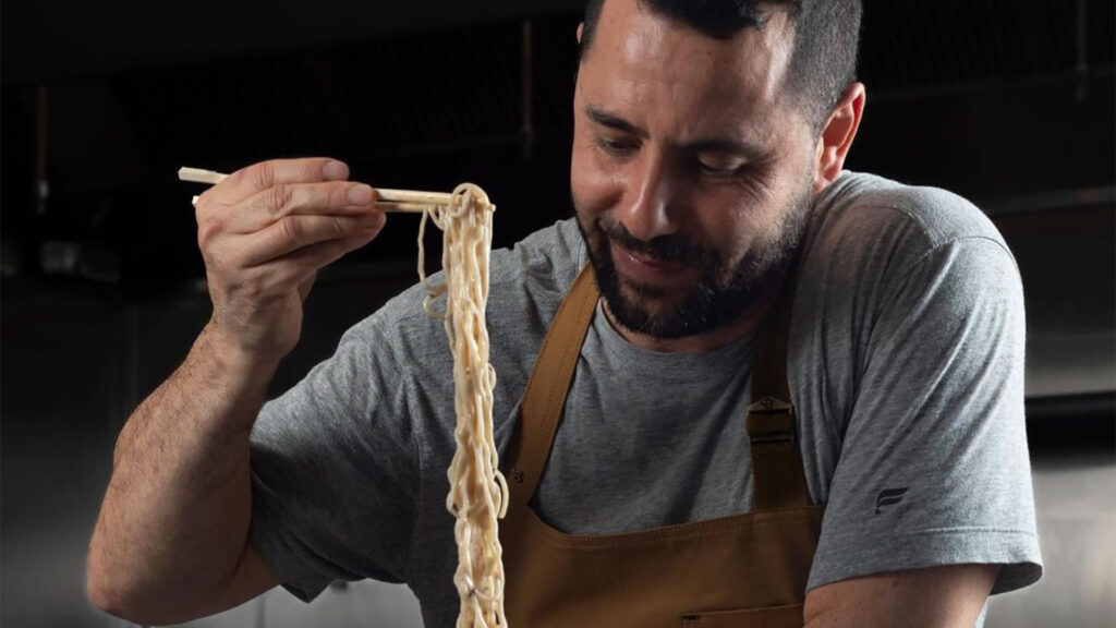 a chef enjoys noodles in the kitchen 