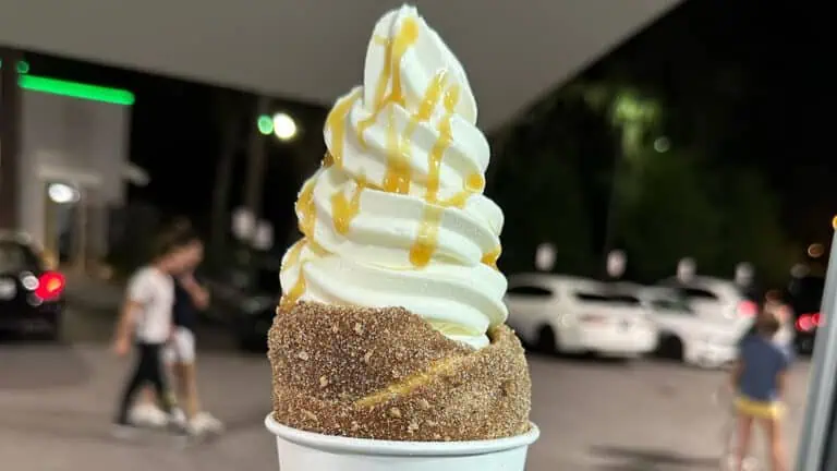 a doughy chimney cake in a white cup filled with vanilla soft serve and caramel