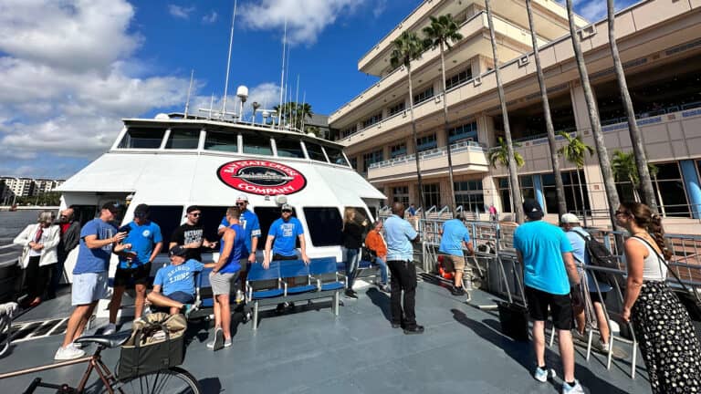 people standing on the front of a ferry as it approaches a dock