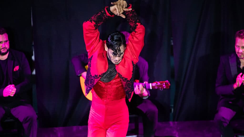 a performer in a bright red outfit dances on stage 