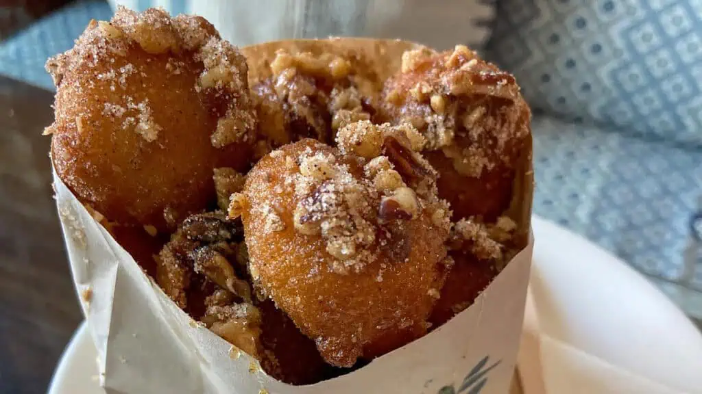 a bag filled with donut holes covered in honey, nuts, and cinnamon sugar