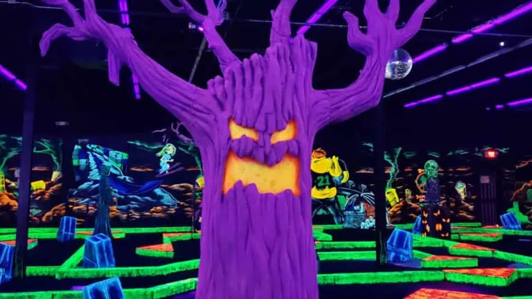 interior of a glow in the dark mini golf course with a creepy tree