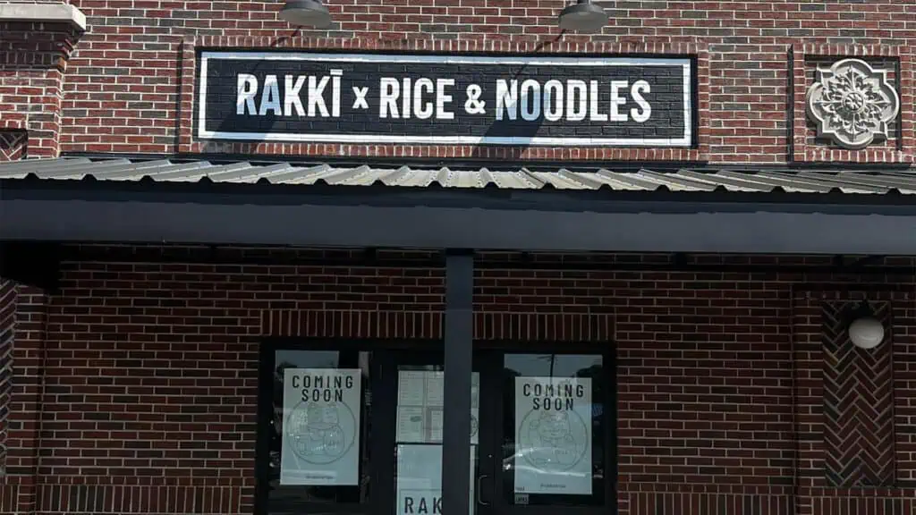 exterior of a restaurant with a brick facade and a black and white sign over the front door