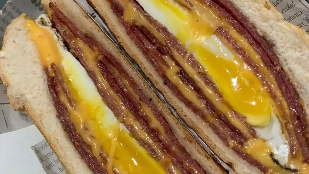 a layered hame egg and cheese breakfast sandwich on a hard roll