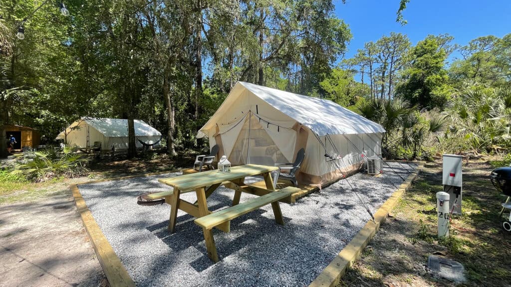 outside a glamping tent with picnic tables out front