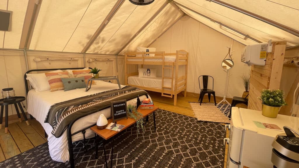 interior o a tent with a full size mattress and bunk beds