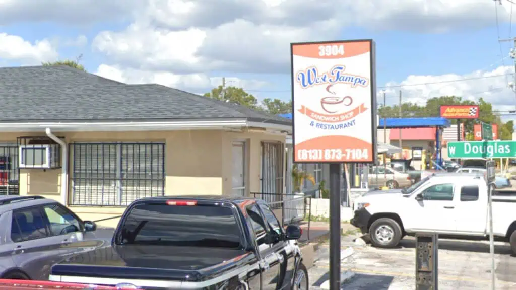 exterior of a sandwich shop with a small white sign out front