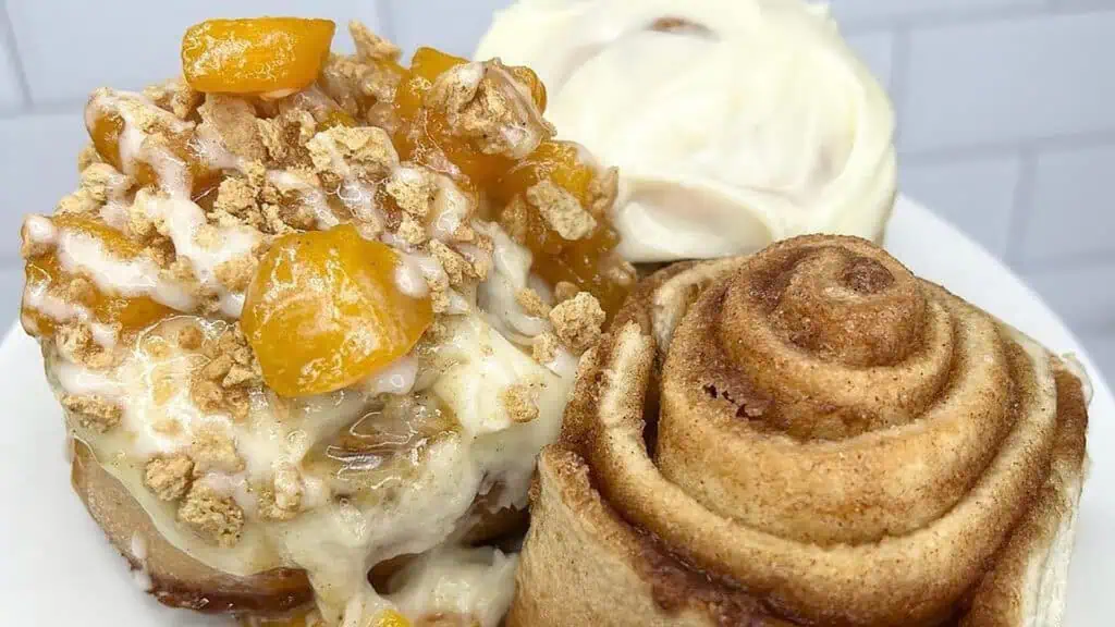 cupcakes, cinnamon rolls and a cake on a plate together