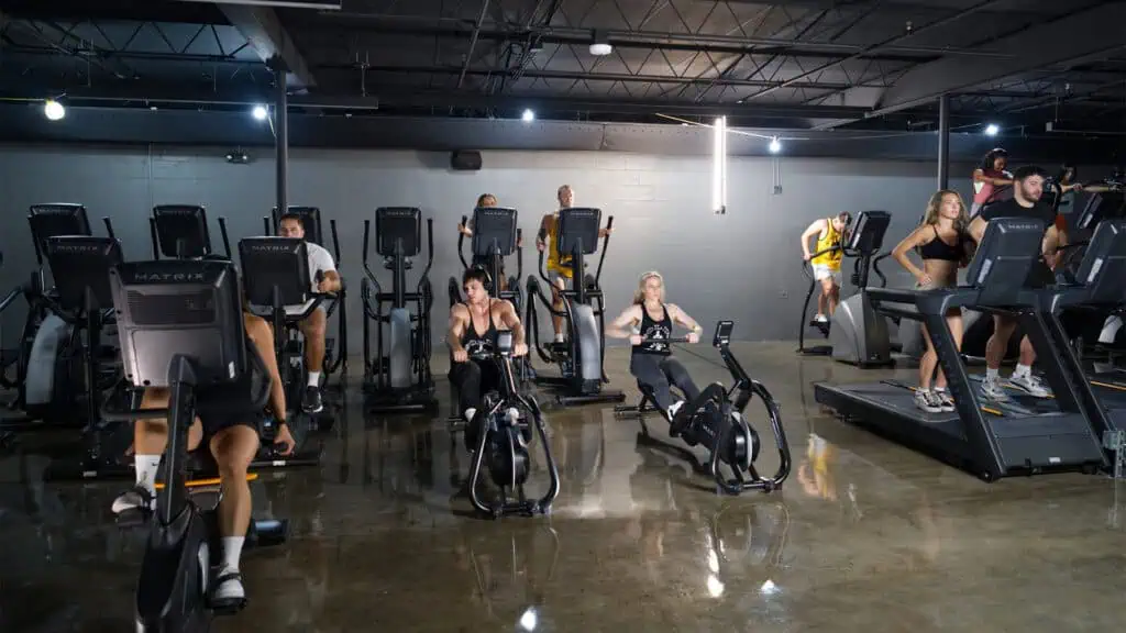 multiple people workout on cardio equipment in a gym