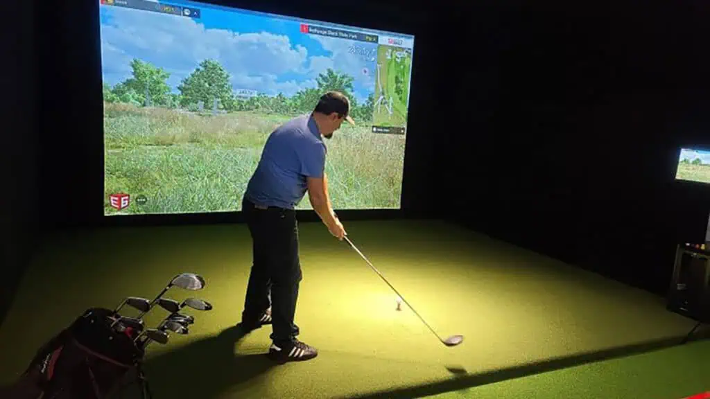 a man lines up a shot on a golf simulator 