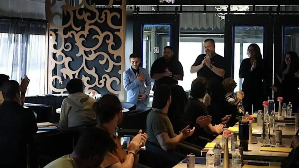 a group of chefs and waitstaff prepping inside of a restaurant 