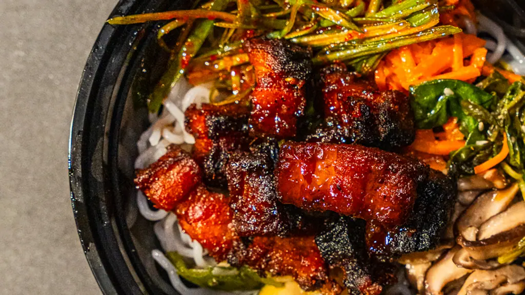 bowl of pork with rice and veggies 