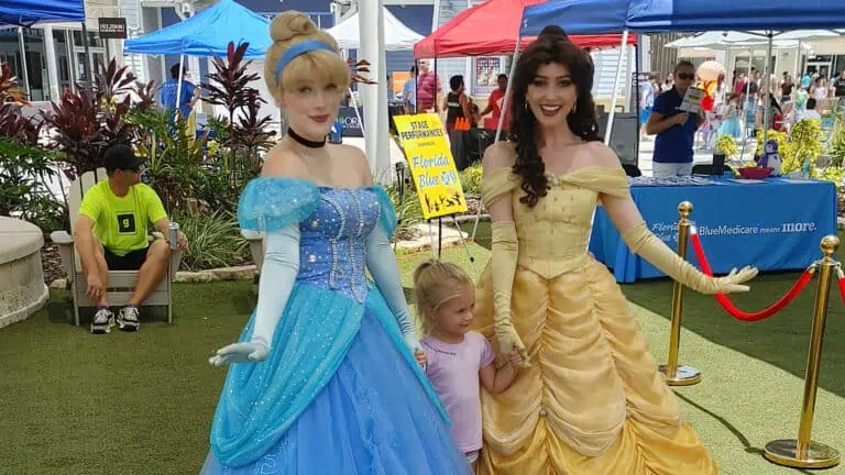 Two Disney princesses pose for photographs at a family-friendly event