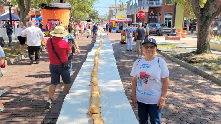 a longe cuban sandwich festival assembled on a long table on a brick street