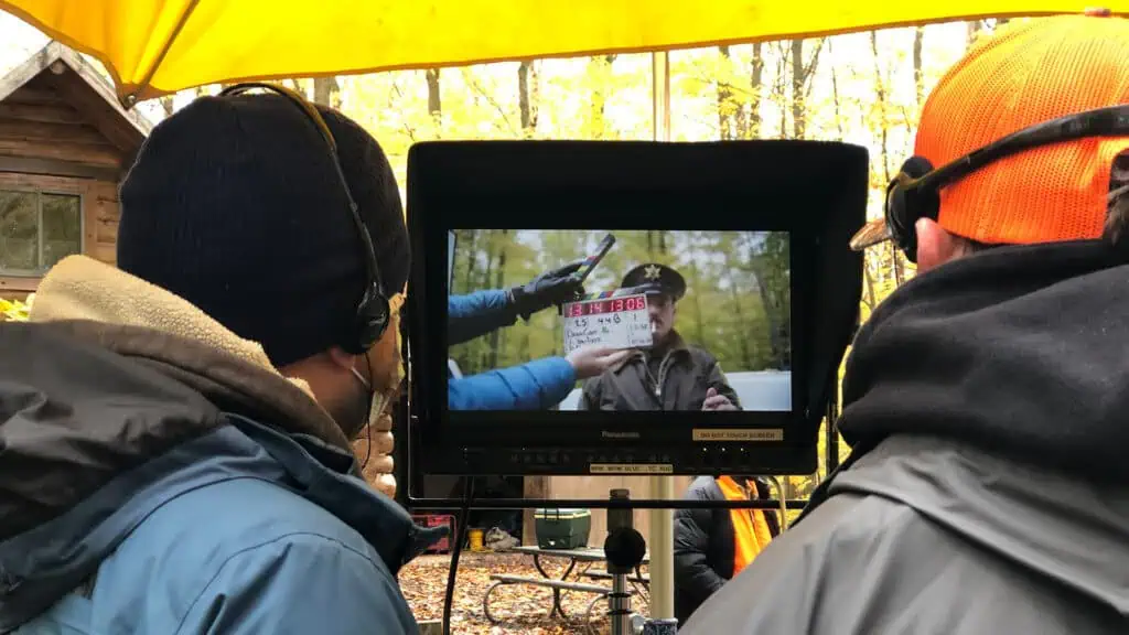 film crown set filming in the woods. A monitor shows the scene