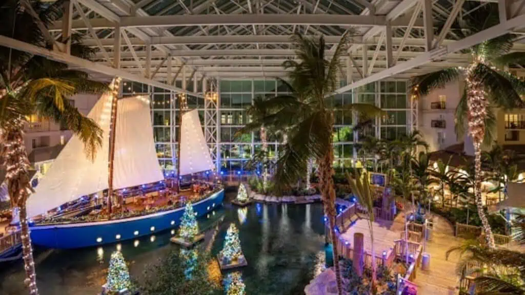 interior of a hotel with a lagoon and sailboat covered in lights 