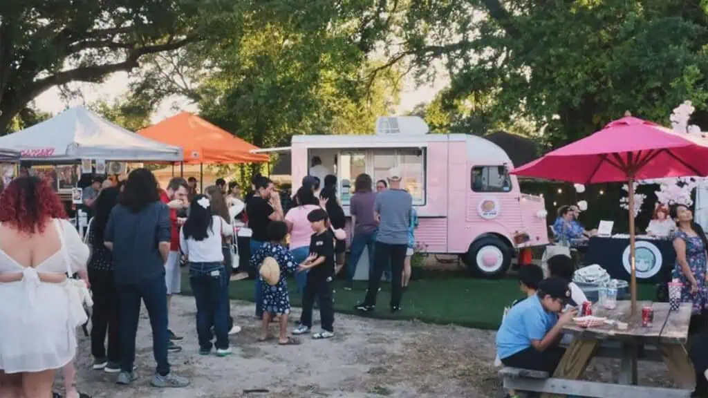 Exterior of a pink truck with a line formed outside