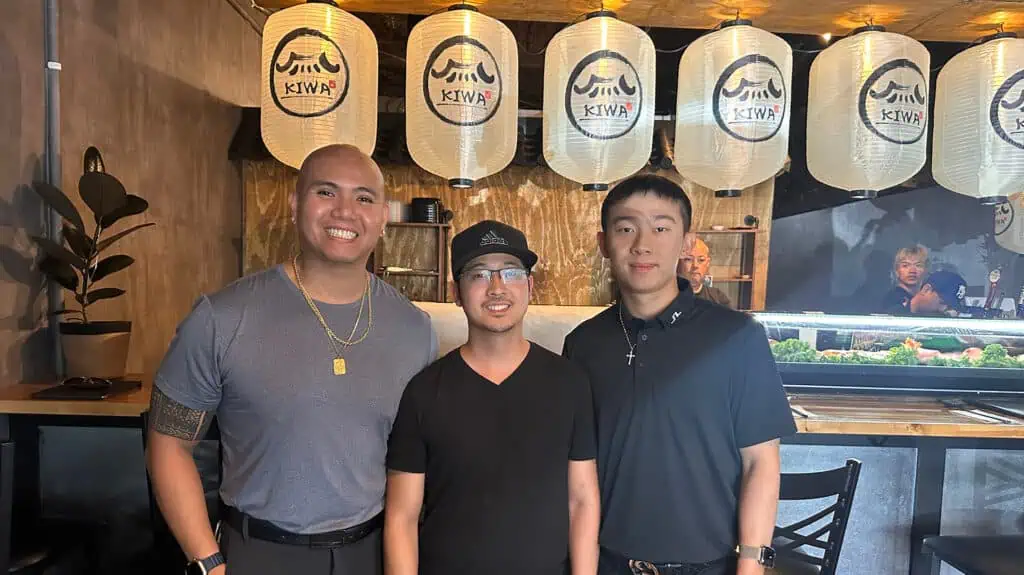 three people stand in front of a bar