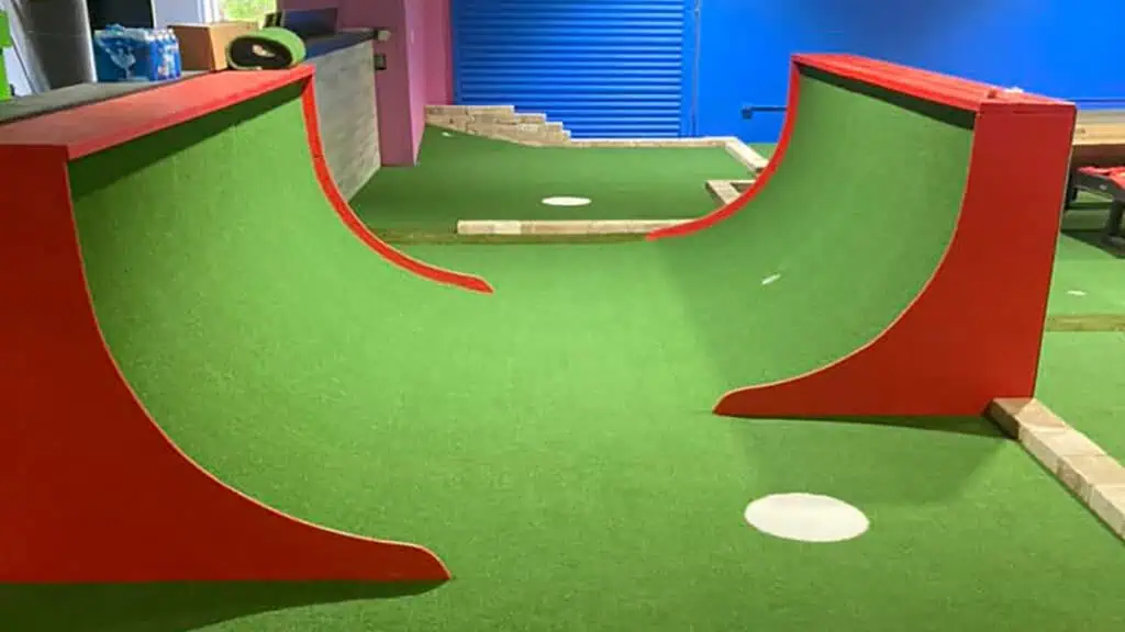 a mini golf course with a half pipe green