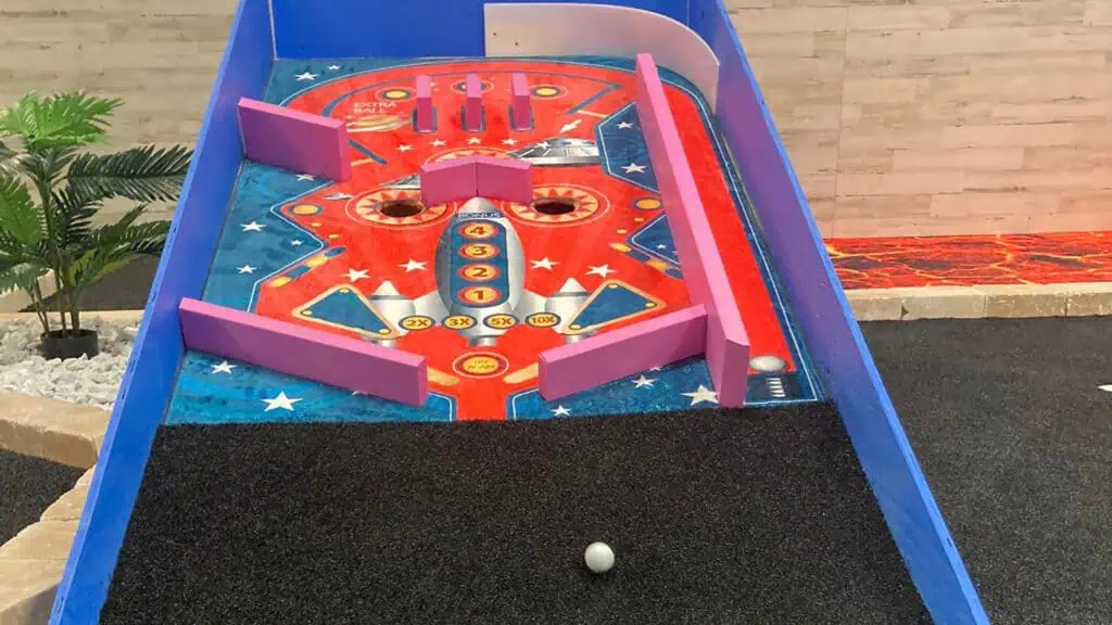 a min golf hole designed to look like a pinball machine