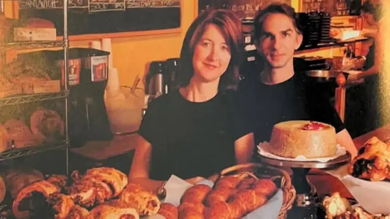 two people standing behind a bread counter