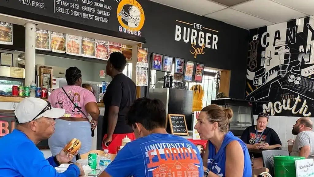 interior of a small burger restaurant with a menu board above the register. 